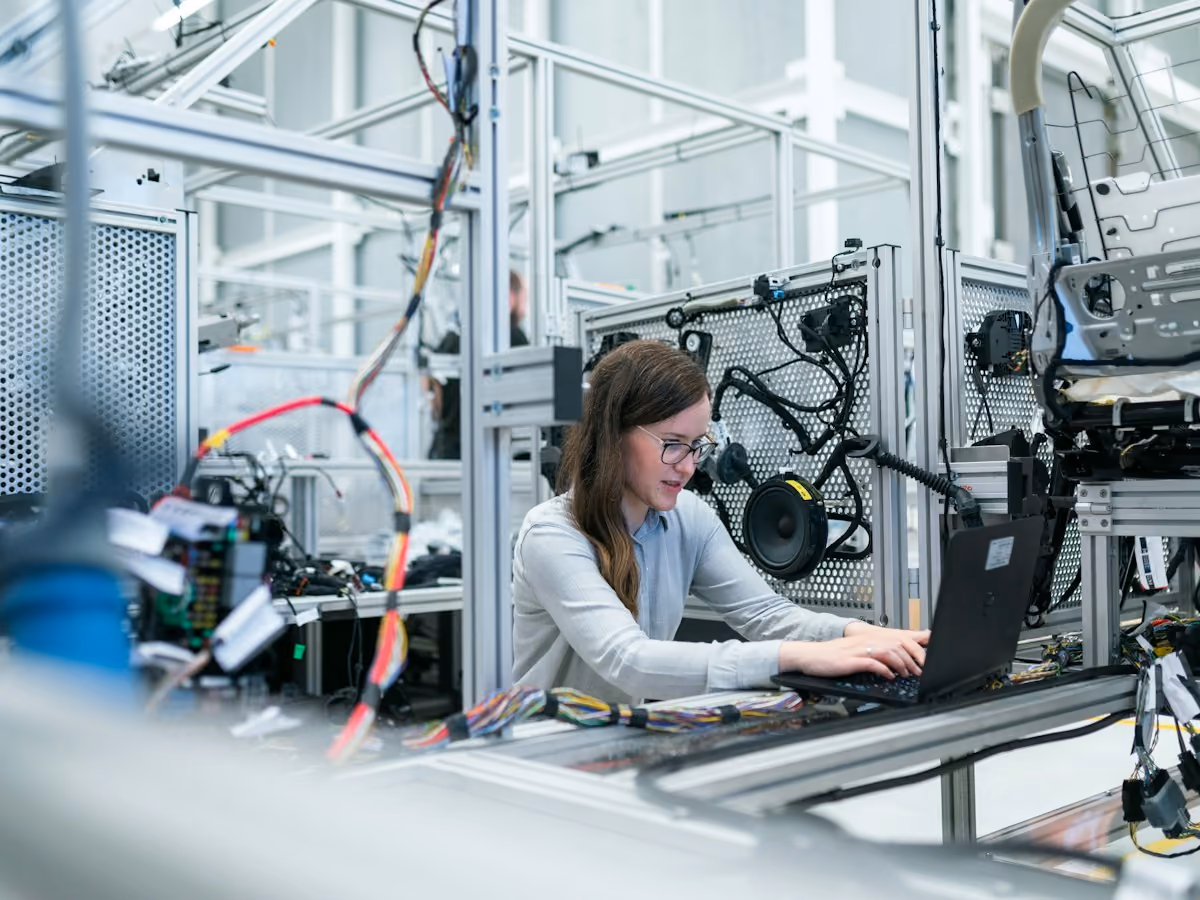 Engineer at a laptop beside an automation cell built on an aluminum frame