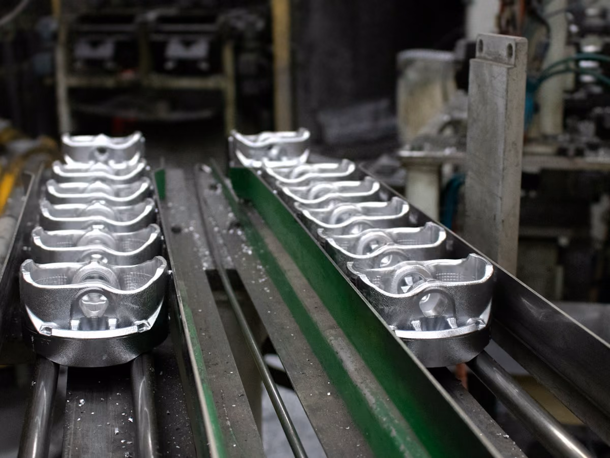 Conveyor beam with side rails carrying machined parts